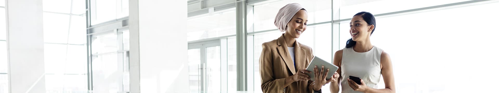 Two young professional women compare notes in brightly lit office