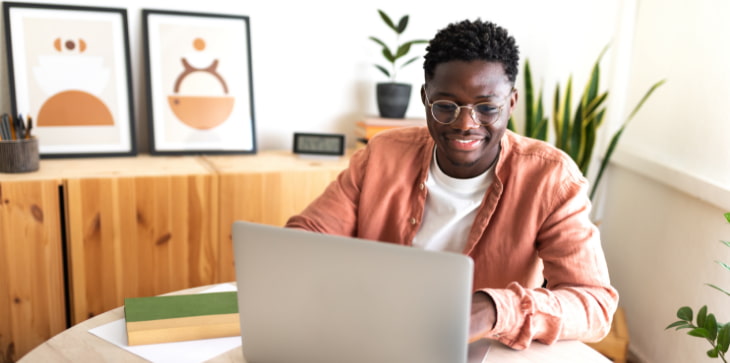 Young man glasses smiling at laptop
