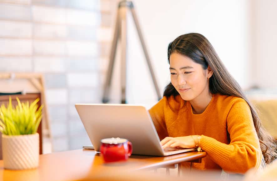 Woman sitting on a desk checking her laptop