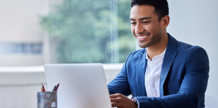 Man smiling at laptop researching